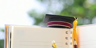 毕业或毕业后出国留学的国际概念，祝贺毕业生帽子上的笔记本用铅笔为拷贝空间。学习通向成功的目标生活。回到学校