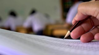 教育考试概念:高中课堂上，学生手持考笔，写答题卡或练习题，在木桌上用复写纸电脑答题视频素材模板下载