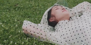 穿着雨衣睡在草地上的漂亮女人