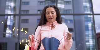 一个穿着粉红色裙子的年轻女孩购物后打开购物袋。缓慢的运动。高清