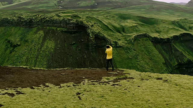航拍探险旅行摄影师站在悬崖边拍摄瀑布山景