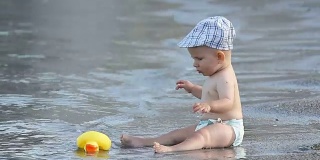 小婴儿坐在海边，他的玩具被海浪带走了