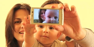 妈妈，爸爸和宝宝用智能手机给自己拍照