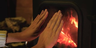 女人把冻僵的手拿到壁炉前取暖