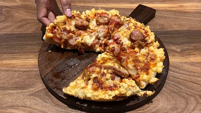 Taking a piece of freshly baked homemade pizza full mash with stretching cheese on table