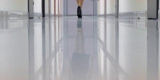 一个穿着黑色高跟鞋的女人走在办公楼的走廊上