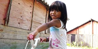 可爱的女孩肖像骑自行车在农村的地方