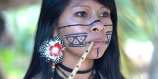土著巴西年轻女子抽烟斗，来自瓜拉尼民族