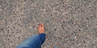 人的腿在柏油路上行走，光着脚在岩石上行走