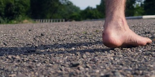 一个男人赤脚走在乡间的石子路上