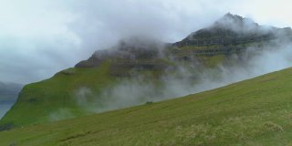 航拍:在雾天飞过空旷的草地，一直飞到长满青草的山上。