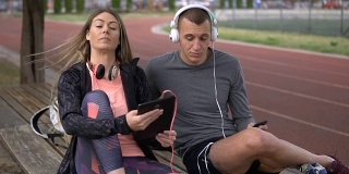 一对运动夫妇在跑道旁欣赏音乐