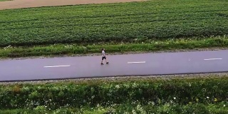那个人走在田野附近的路上。quadrocopter拍摄