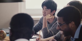 特写快乐的日本年轻员工听和笑在一起的同事在多民族办公室会议