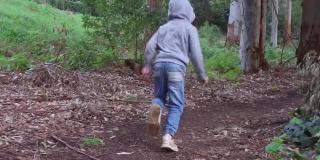 一个小男孩在茂密的森林里奔跑