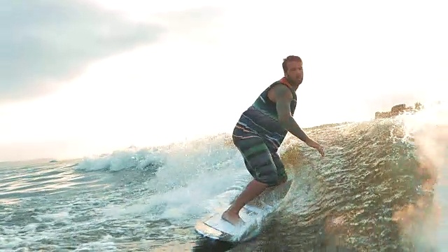 活跃的男子在慢动作浪中冲浪。水上滑水横渡河流。