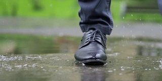 一个穿着黑鞋的男人踩进水坑里，慢镜头180帧/秒