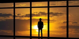这个男人站在日落背景的全景窗户旁。时间流逝