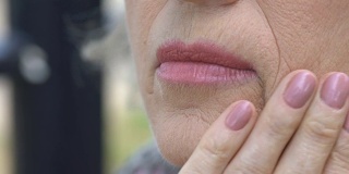 老年妇女抚摸着她布满皱纹的脸庞，皮肤老化的过程，渴望年轻