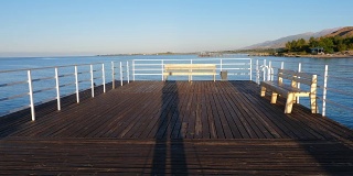 伊塞克-库尔湖上的长木码头上的摄影师的影子