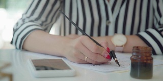 女性手持书法笔，在网上观看范例