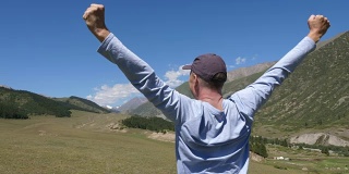 旅行者举起双手庆祝绿色山谷的成功
