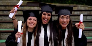 甜蜜的一组三个女性朋友看着相机微笑庆祝他们刚刚毕业