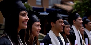 一群兴高采烈的拉丁美洲学生在毕业典礼上拿着他们的学位