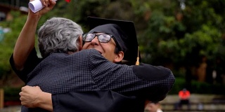 年轻的男学生在获得大学学位后拥抱他的父亲，非常高兴