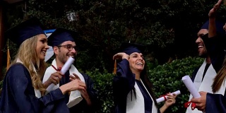 一群兴高采烈的成年学生庆祝他们刚刚毕业，他们笑着击掌庆祝