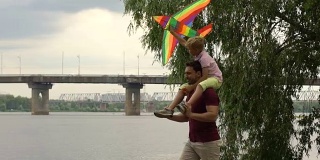 父亲和儿子在河边放风筝，快乐的时光在一起，父母的爱