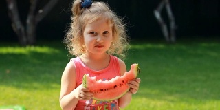小女孩吃了一个西瓜。宝宝在夏天吃东西。特写肖像