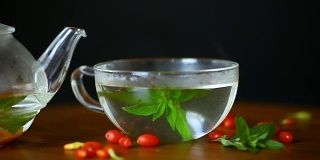 用玻璃茶壶盛着熟透的红枸杞的热茶