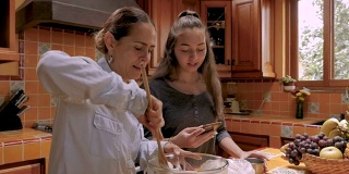 十几岁的女儿用手机帮她的墨西哥妈妈烤面包