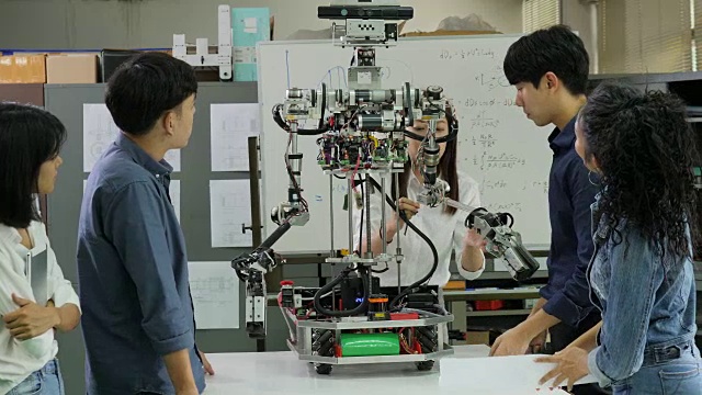 年轻的电子工程师团队在车间协作建造机器人。团队工程师一起启动机器人项目。有技术或创新观念的人。