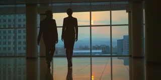 一个男人和一个女人走在办公室大厅里。慢动作