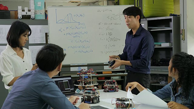 在计算机科学课上，老师与学生谈论机器人技术。男工程师与团队一起参与项目。有技术或创新观念的人。