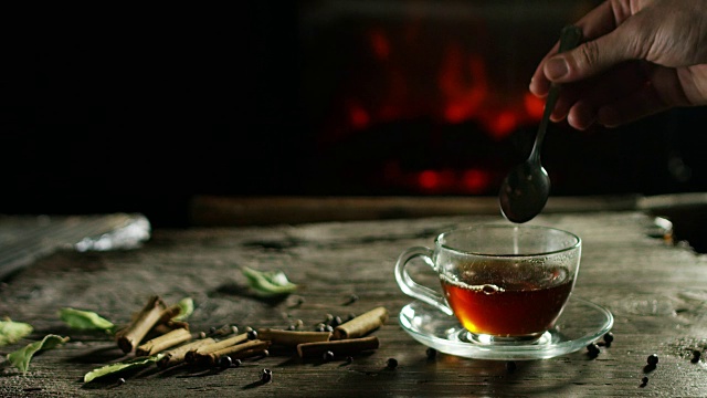 美丽浪漫的草药茶和茶的组合，它被倒在一个古老的木制砧板上，背景是香料和壁炉