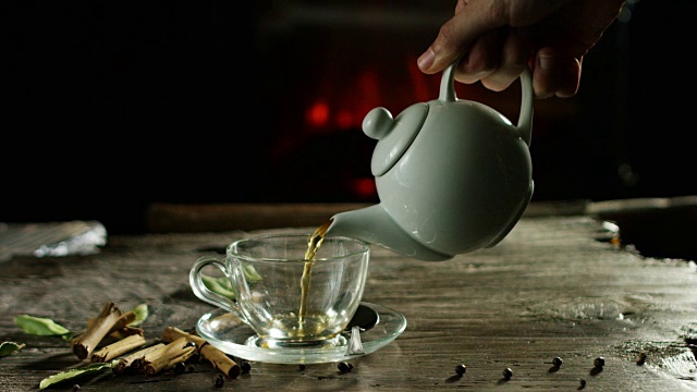 美丽浪漫的草药茶和茶的组合，它被倒在一个古老的木制砧板上，背景是香料和壁炉