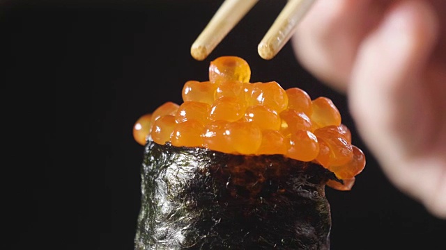 寿司，生鱼片，浦城和夜拍的微距镜头。典型的日本菜，包括米饭、鲑鱼或金枪鱼、虾和浸在酱油中的鱼卵。