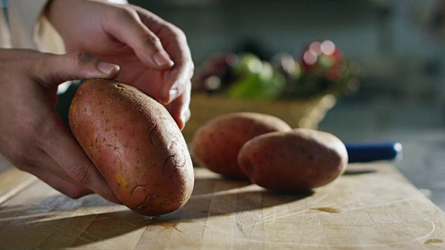 一个中年厨师的手在餐厅厨房里削生土豆的超级慢动作