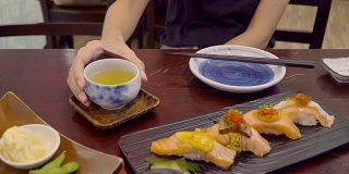 亚洲妇女喜欢吃日本寿司和绿茶在午餐时间在日本餐厅