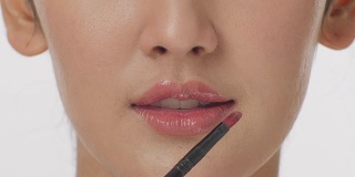近距离肖像化妆师用口红刷性感的嘴唇有吸引力的女人。化妆的嘴唇。美丽和时尚的概念。