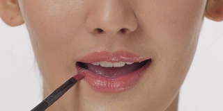 近距离肖像化妆师用口红刷性感的嘴唇有吸引力的女人。化妆的嘴唇。美丽和时尚的概念。