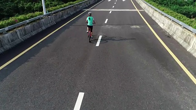 鸟瞰图经验丰富的妇女双手自由骑自行车在高速公路上骑自行车