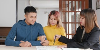 房地产经纪人解释亚洲夫妇关于合同和丈夫在新家签订房屋合同。购买新的房地产