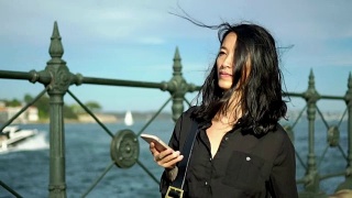一名年轻的成年女子在悉尼海港大桥旁休息，用智能手机打字视频素材模板下载