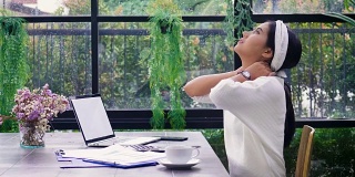 年轻的亚洲女性在家里工作时颈部疼痛，办公室综合症概念