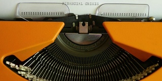 一个人在一台老式打字机上用声音写“金融危机”的高角度镜头
