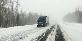 汽车行驶在积雪覆盖的公路上。